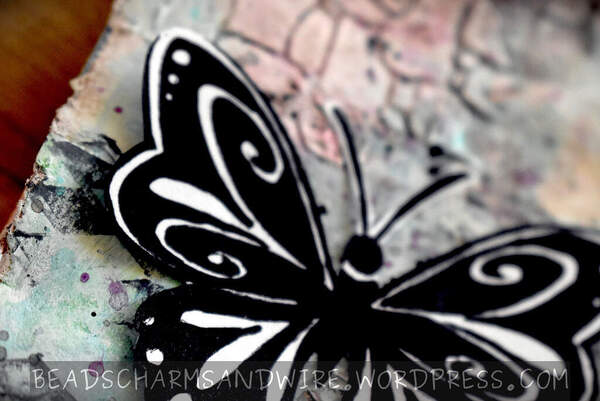 Closeup of art journal page with textured background and a black-and-white butterfly in the foreground