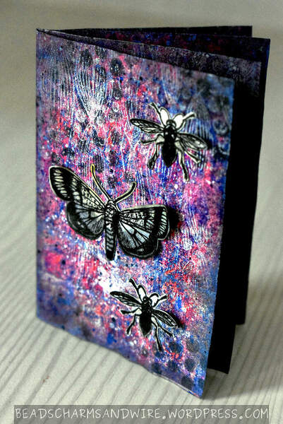 A grungy zine journal with insects as focal objects, and a grungy blue/pink background with traces of dark-gray polka dots, white wavy/leafy curves, and lots of tiny splatters.