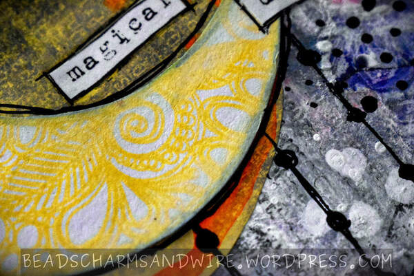 Closeup of an art journal page showing a grungy, scrappy background in white, gray, and blue, with a lot of black and white marks on it. A patterned yellow moon is in the foreground over a stamped yellow, orange, and black disc.